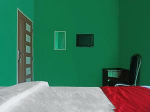 ein Schlafzimmer mit grünen Wänden, einem Bett und einem Stuhl in der Unterkunft OYO 92377 Wisma Melyro Syariah 