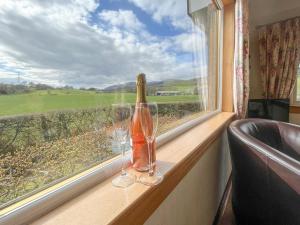 eine Flasche Wein und zwei Gläser auf einem Fenster in der Unterkunft Gean Cottage in Powmill