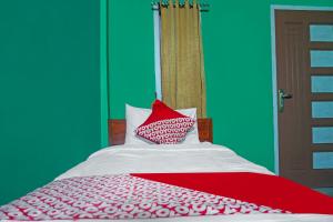 a bedroom with a bed with a red and white blanket at OYO 92377 Wisma Melyro Syariah 