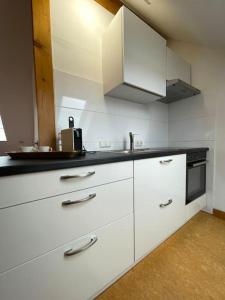 cocina con armarios blancos y encimera negra en Apartment Blattgold, en Schwabach