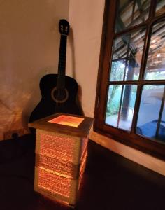 una guitarra y una caja junto a una ventana en Goura House Ilhabela, en Ilhabela