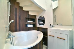 een badkamer met een wit bad en een wastafel bij La Maison des Rivages - Proche plages et Golf in Saint-Briac-sur-Mer