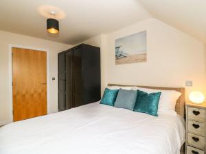 a bedroom with a white bed with blue pillows at Harbour Reach 6 in Weymouth