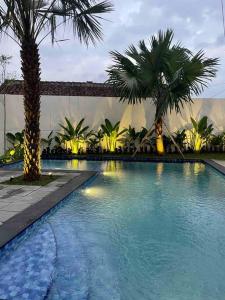 einen Pool mit Palmen in einem Resort in der Unterkunft Dhanis House 7 Bedroom Villa in Cibanawak