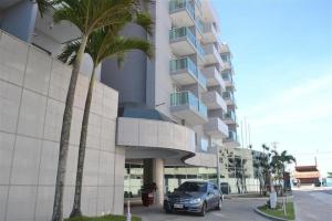 a car parked in front of a building with palm trees at Studio TOP pra homeoffice, internet voando in Macaé