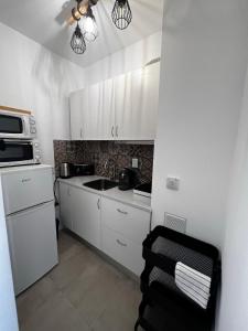 a small kitchen with white cabinets and a sink at Seaview, beach front, studio in Alvor