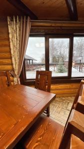 una mesa de madera y sillas en una habitación con ventana en На ставку, en Vyzhnytsya