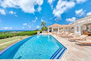 a swimming pool in front of a house with chairs at Villa Mer Soleil in Marigot