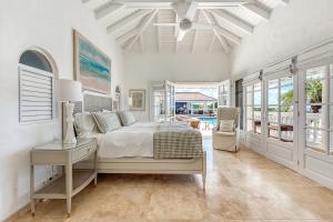 a bedroom with a bed and a table and windows at Villa Mer Soleil in Marigot