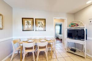 a dining room with a table and a tv at Seahorse 612 in Gulf Shores
