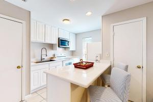 a kitchen with white cabinets and a table with chairs at Seahorse 612 in Gulf Shores +14 photos