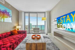 a living room with a red couch and a tv at EXCLUSIVE RESORT - OCEANFRONT 2BD 2BA CONDO, HiGH FLOOR, ROOFTOP POOL AND HOT TUB, STEPS TO BEACH in Hollywood