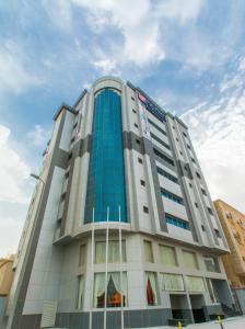 a tall white building with blue windows at Baisan Suites Al Jubail in Al Jubail