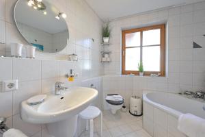 La salle de bains blanche est pourvue d'un lavabo, d'une baignoire et d'un miroir. dans l'établissement Ferienwohnung Ferienparadies, à Füssen