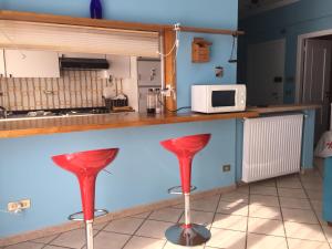 une cuisine avec des tabourets rouges et un comptoir avec un four micro-ondes dans l'établissement Vacanze a Finale Ligure, à Finale Ligure