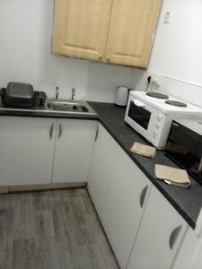 een kleine keuken met een magnetron en een wastafel bij Litherland Apartment in Litherland
