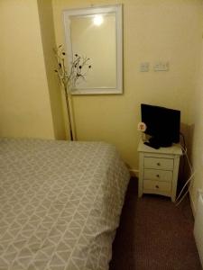 a bedroom with a bed and a desk with a computer on it at Litherland Apartment in Litherland