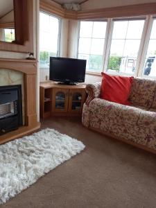 un soggiorno con divano e TV a schermo piatto di Adorable Caravan in Western Lakes a Workington