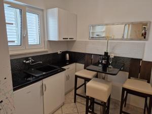 cocina con armarios blancos, mesa y sillas en Apartments Jagoda, en Podstrana