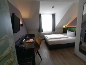 a hotel room with a bed and a desk at Art Hotel Aachen in Aachen