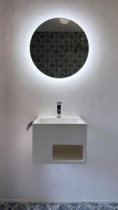 baño con encimera blanca y espejo redondo en Villa Usignolo, en Lignano Sabbiadoro