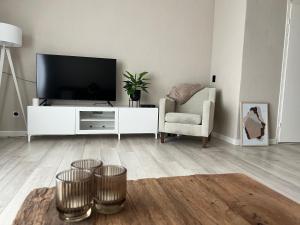 uma sala de estar com uma televisão e uma cadeira em New modern apartment (55m2) in the city center em Enschede