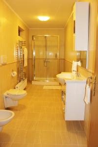 a yellow bathroom with two sinks and a shower at City Inn Residence in Timişoara