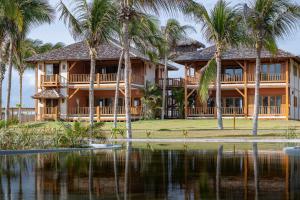 a house on the water with palm trees at Jaguaríndia Village in Fortim