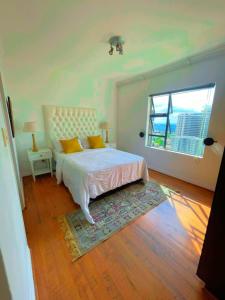 ein Schlafzimmer mit einem Bett mit gelben Kissen und einem Fenster in der Unterkunft The Westpoint Penthouse in Johannesburg