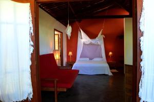 a bedroom with a bed and a red wall at Floresta Bungalows in Imbassai