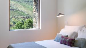 een slaapkamer met een bed en een raam met uitzicht bij Quinta de Merouço - Villa do Rolapipas in Alijó