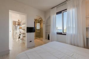 Un dormitorio blanco con una cama grande y una ventana. en Apartamento Talaia by MarCalma, en Mont-roig