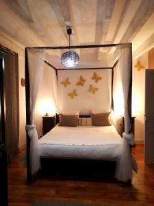 ein Schlafzimmer mit einem Himmelbett mit weißer Bettwäsche und Kissen in der Unterkunft Passiflore au Mas d'Escampette in Soupex