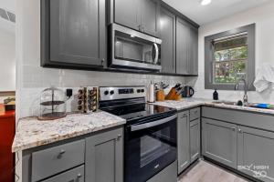 una cocina con armarios grises y electrodomésticos negros en Alyce Retreat - Nature, Trails and Lake Escape, en Bella Vista