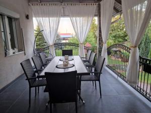 a dining table and chairs on a balcony with curtains at PanOli Apartmanház Nyíregyháza in Nyíregyháza