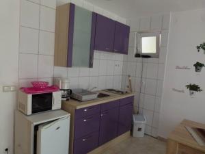 a kitchen with purple cabinets and a microwave at Apartmani Ivanic in Vir