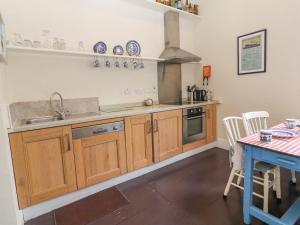 cocina con armarios de madera, fregadero y mesa en The Merchant's House, en Kilrush