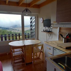 a kitchen with a table and a window with a view at Avec Wifi - Studio en pleine nature Puyvalador in Puyvalador