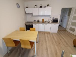 eine Küche mit weißen Schränken sowie einem Holztisch und Stühlen in der Unterkunft Prague Gardens Appartments in Prag