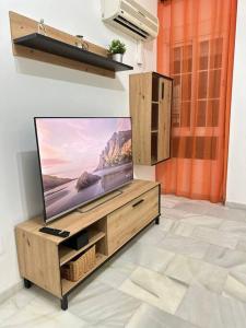 TV de pantalla plana en un centro de entretenimiento de madera en Moderno apartamento junto al mar- Apartamentos Don Diego, en Torremolinos