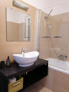 La salle de bains est pourvue d'un lavabo blanc et d'une douche. dans l'établissement Zamárdi apartman, à Zamárdi
