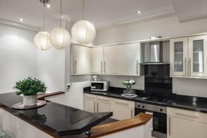 eine Küche mit weißen Schränken und schwarzen Arbeitsplatten in der Unterkunft Park Street Mayfair apartments in London