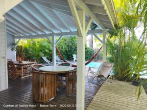 a wooden deck with a pergola and tables and chairs at Villa Van Gogh aux Aquarelles in Sainte-Rose