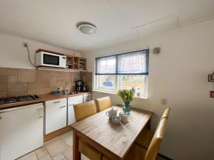 Vakantiewoning aan Zee - 150m van het Strand في إغموند آن زي: مطبخ مع طاولة خشبية مع كراسي وميكروويف