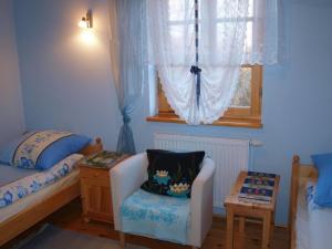 a bedroom with a bed and a chair and a window at Wejmutka, Białowieża in Białowieża