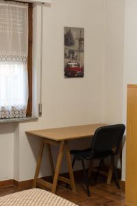 einem Holztisch mit einem schwarzen Stuhl neben einem Fenster in der Unterkunft Mufasa B&B in Soverato Marina