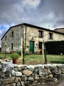 een stenen gebouw met een groene deur en een stenen muur bij Vitalba by Gallo in Chianni