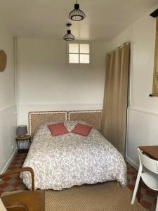 um quarto com uma cama com duas almofadas vermelhas em Studio épicéa avec jardin dans charmante propriété em Méry-sur-Oise