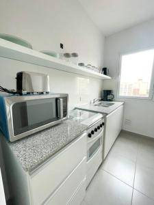 a white kitchen with a microwave on a counter at Saavedra 118 2°C by depptö in Bahía Blanca
