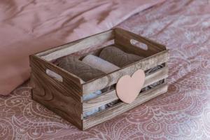a wooden box with towels and a heart on a bed at Apartman Ponte Martini in Punat